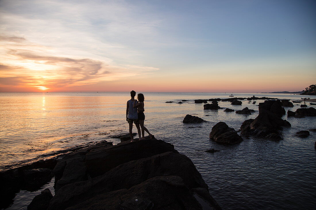 Silhouette von jungem Paar auf Felsen am Ong Lang Beach bei Sonnenuntergang, Ong Lang, Insel Phu Quoc, Kien Giang, Vietnam, Asien