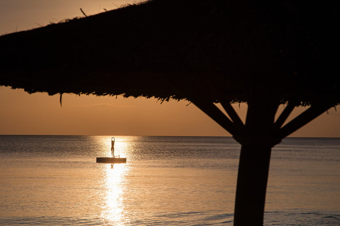 Silhouette von strohgedeckten Sonnenschirm und junger Frau auf Badeplattform im Wasser vor dem Ong Lang Beach, Ong Lang, Insel Phu Quoc, Kien Giang, Vietnam, Asien