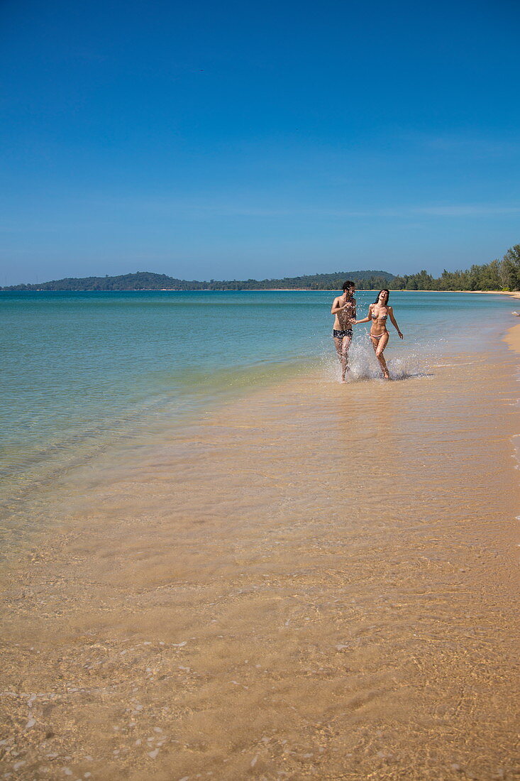 Young couple runs along the water's edge at the seemingly endless Van Beach, near Cua Can, Phu Quoc Island, Kien Giang, Vietnam, Asia