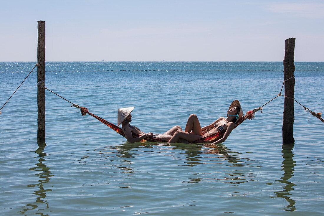 Paar entspannt sich in schwimmender Hängematte im Chez Carole Phu Quoc Resort am Ong Lang Beach, nahe Cua Can, Insel Phu Quoc, Kien Giang, Vietnam, Asien