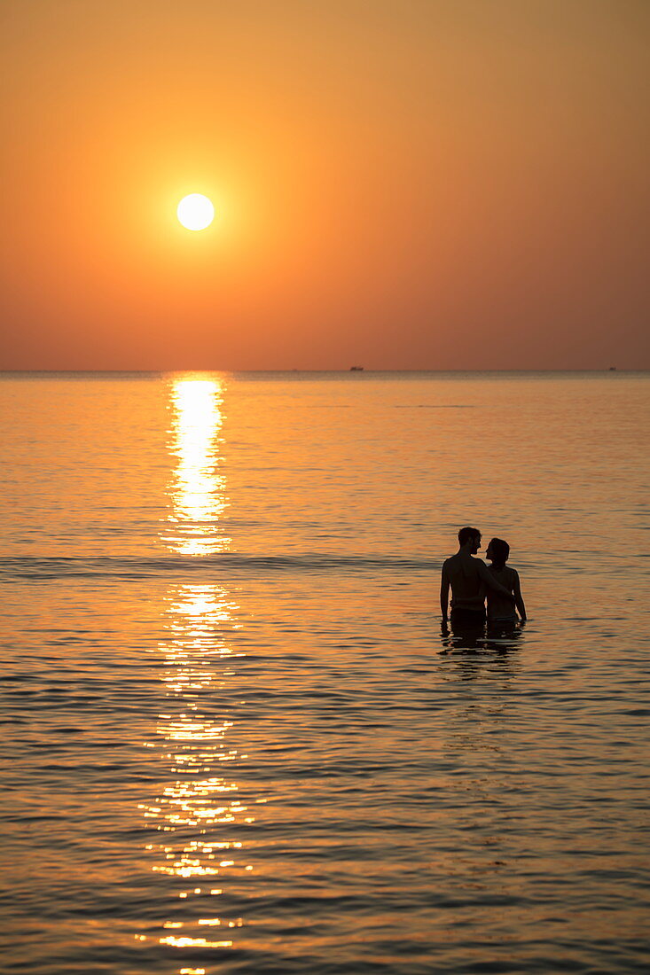 Silhouette of a romantic young couple in the water in front of Ong Lang Beach at sunset, Ong Lang, Phu Quoc Island, Kien Giang, Vietnam, Asia