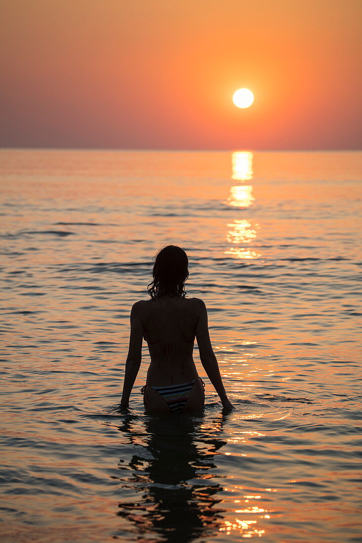 Silhouette of young woman in the water in front of Ong Lang Beach at sunset, Ong Lang, Phu Quoc Island, Kien Giang, Vietnam, Asia