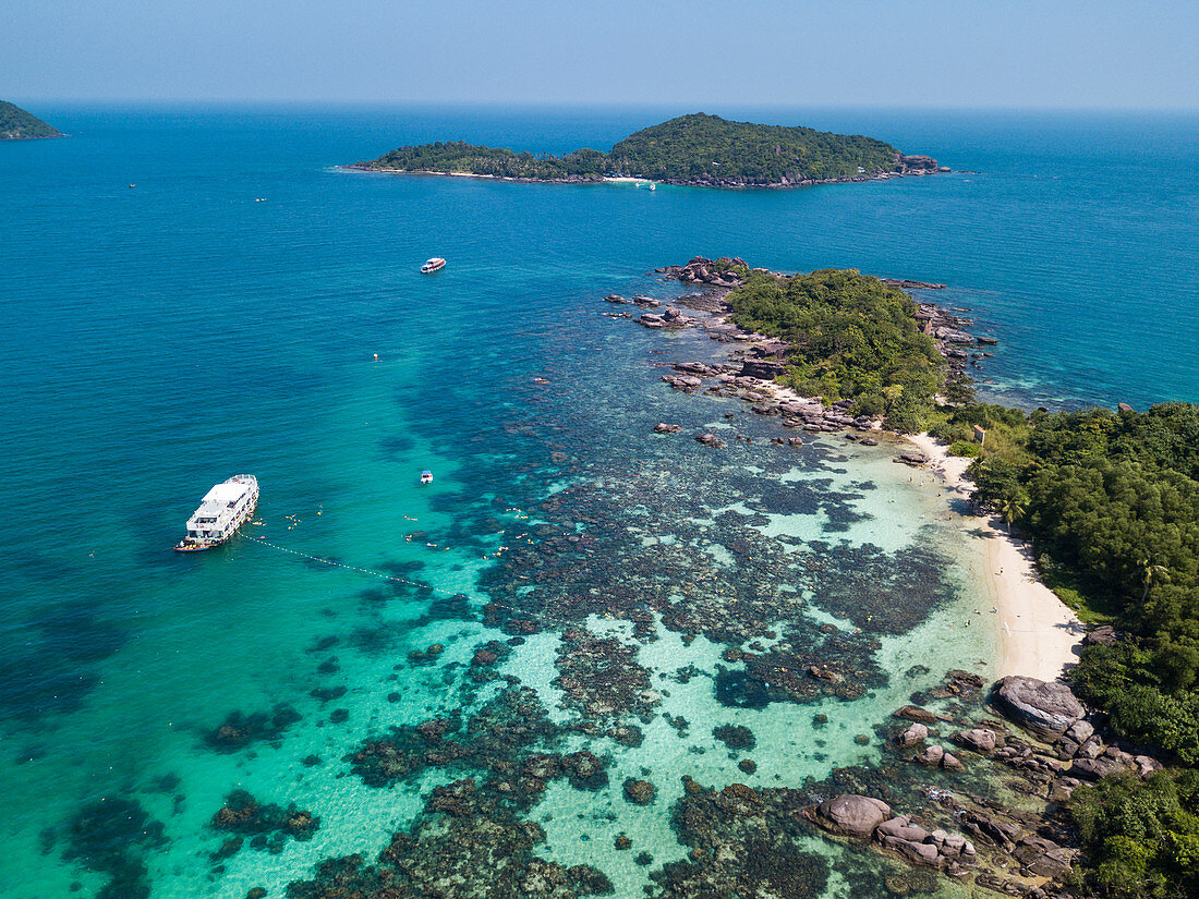 Aerial view of John's Tours No. 9 excursion boat and tourists snorkeling in clear water near beach with coconut palms, Dam Ngang Island, near Phu Quoc Island, Kien Giang, Vietnam, Asia