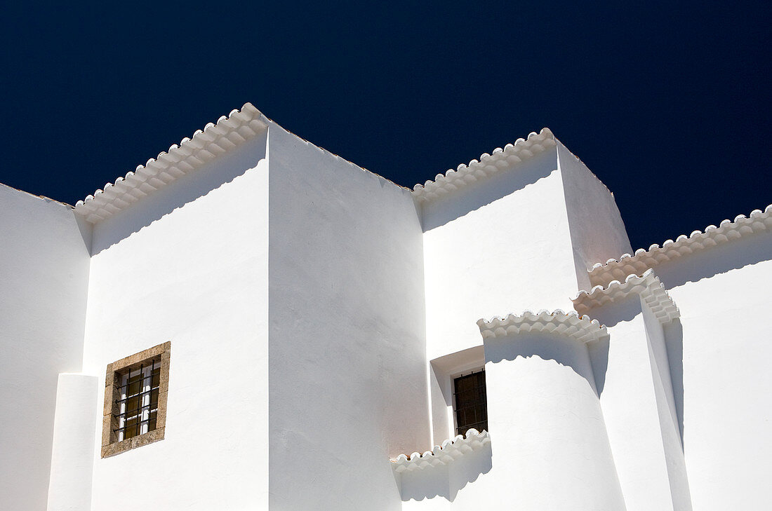 Ein weißes Wohngebäude vor einem dunkelblauen Himmel. Die Gebäude sind in traditioneller Architektur an der Algarve in Portugal gebaut.