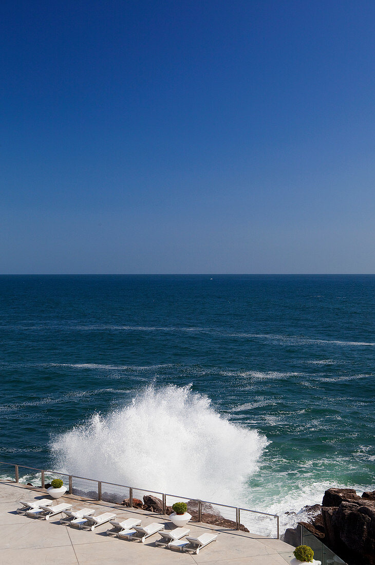 A huge break against a pool deck set with an ocean view, shot near Cascais in Portugal.