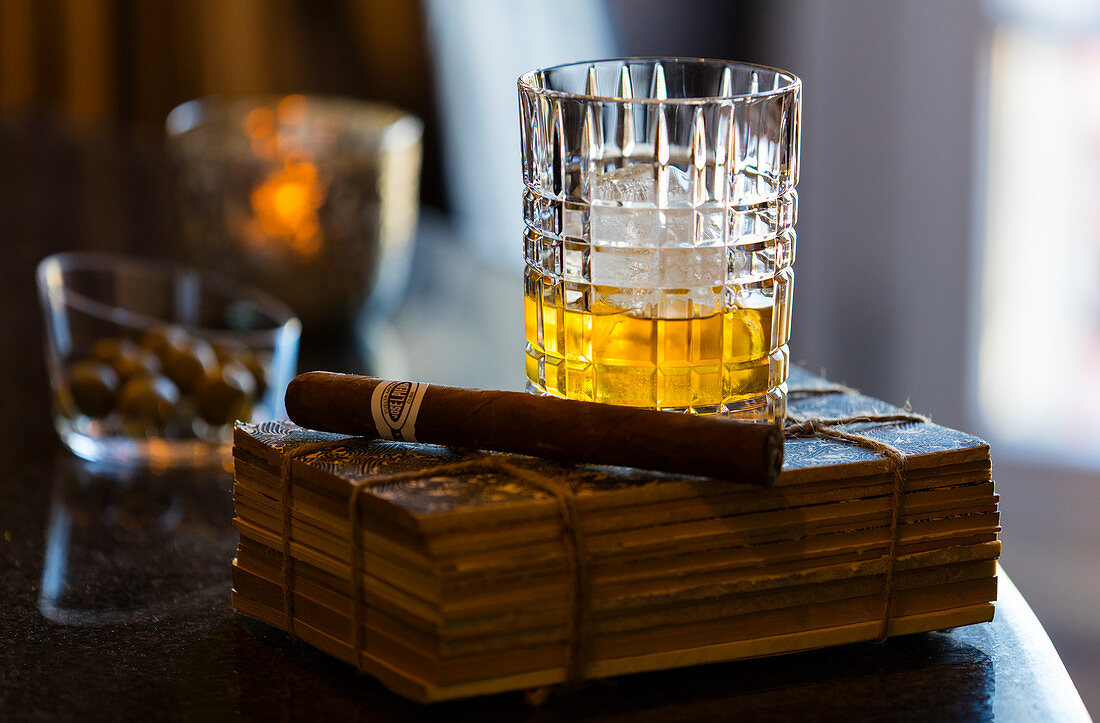 Stillleben ein Glas Whisky mit einer Zigarre auf einem alten Buch. Algarve, Portugal.