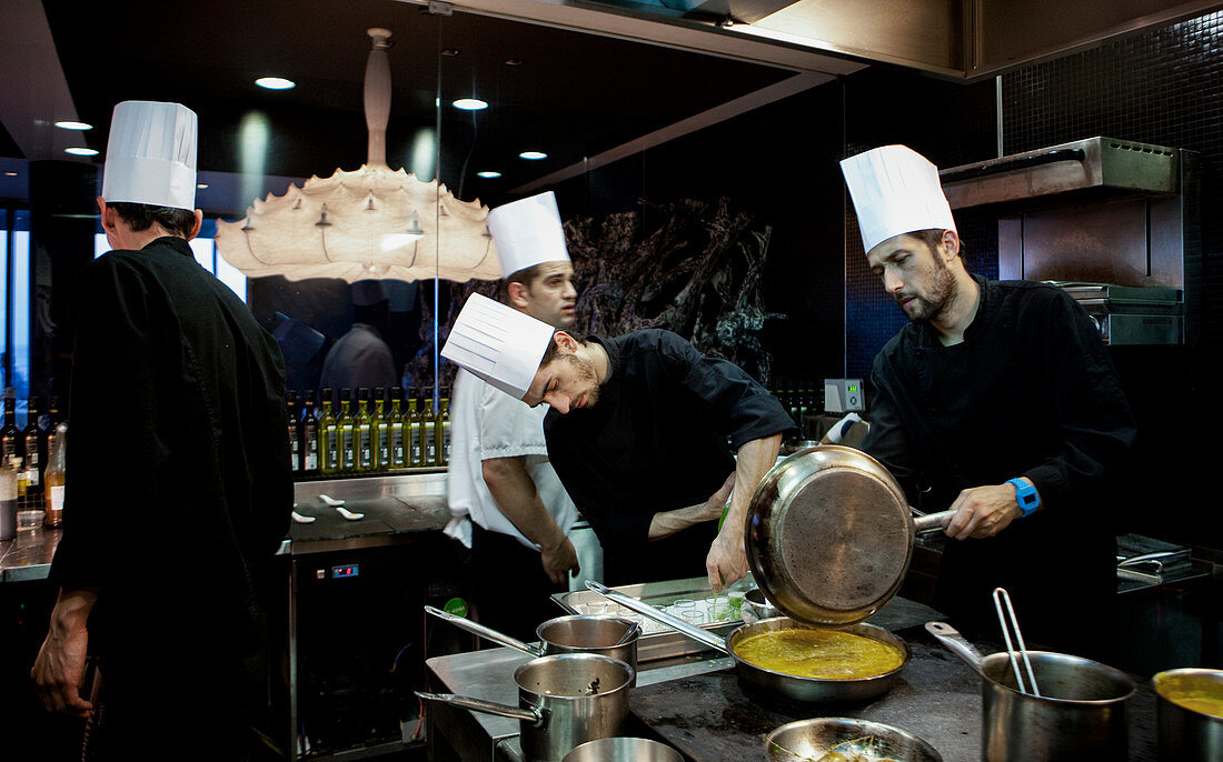 A busy kitchen scene with 4 chefs cooking