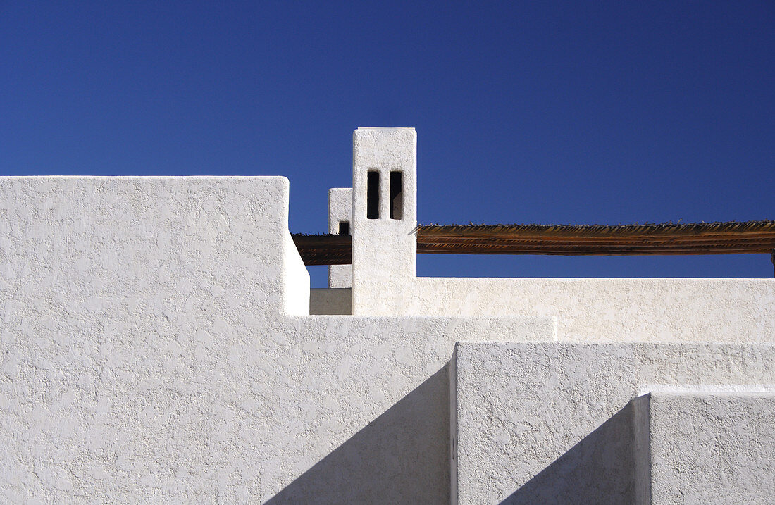 Aufnahme eines weißen, charakteristischen Hauses im Cabo-Stil, weiß getüncht und mit einer Palapa-Dachabdeckung. Cabo San Lucas, Mexiko.