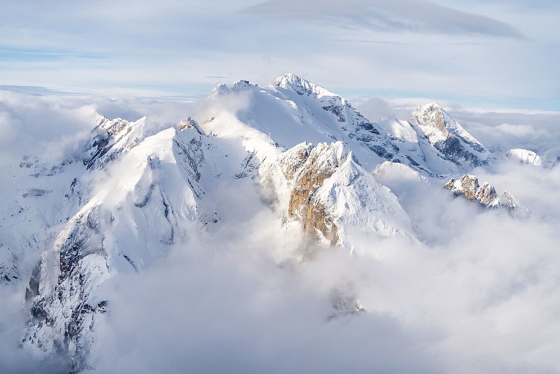 Wolken, die die schneebedeckte Marmolada umgeben, Luftaufnahme, Dolomiten, Trentino-Südtirol, Italien