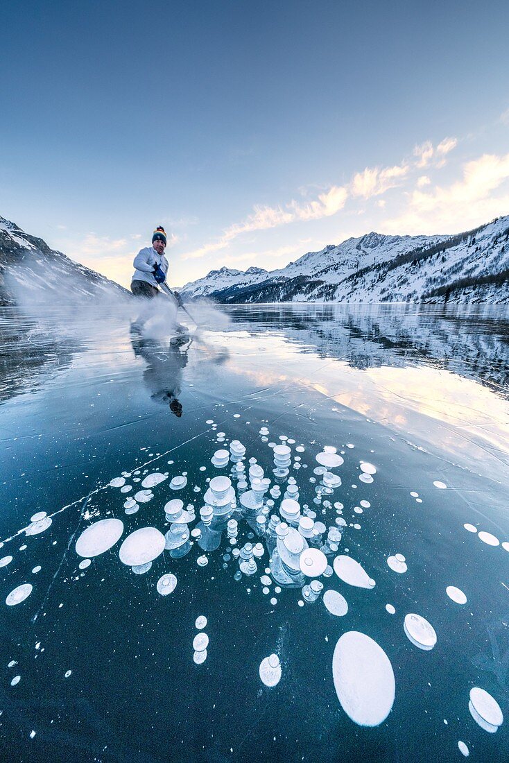 Eishockeyspieler, der Spaß hat, Eispulver in die Luft zu werfen, Silssee, Kanton Graubunden, Engadin, Schweiz
