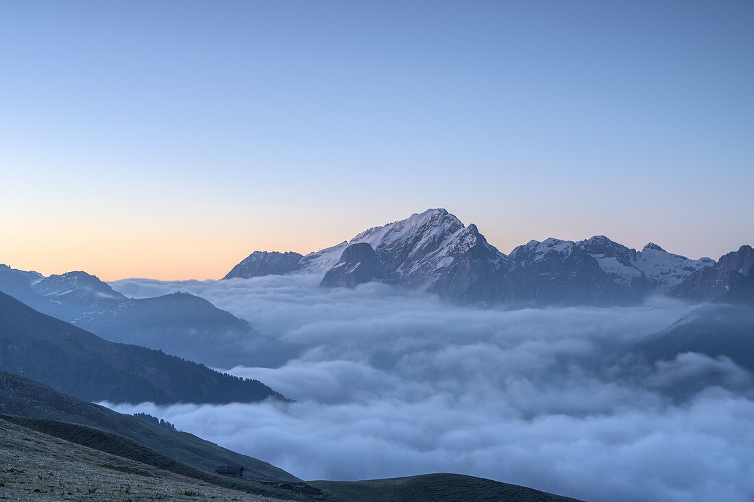 Dusk over Marmolada emerging from a sea of clouds, Dolomites, Trentino, Italy