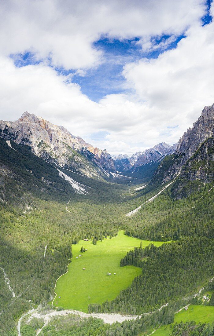 Aerial panoramic of green valley and woods framed by mountain peaks, San Vigilio di Marebbe, Dolomites, South Tyrol, Italy