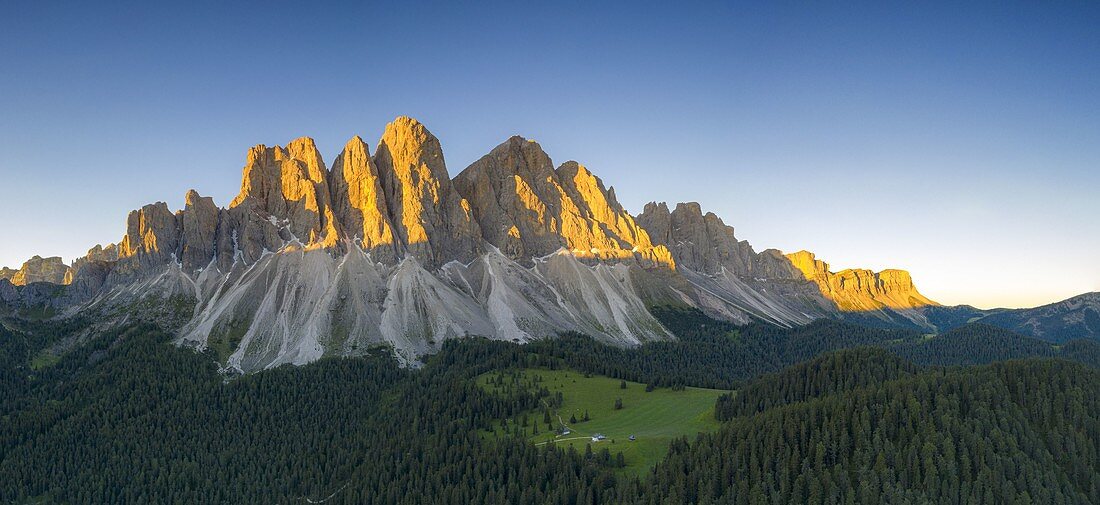 Odle Gipfel beleuchtet von Sonnenaufgang umgeben von grünen Wäldern im Sommer, Val di Funes, Südtirol, Provinz Bozen, Dolomiten, Italien