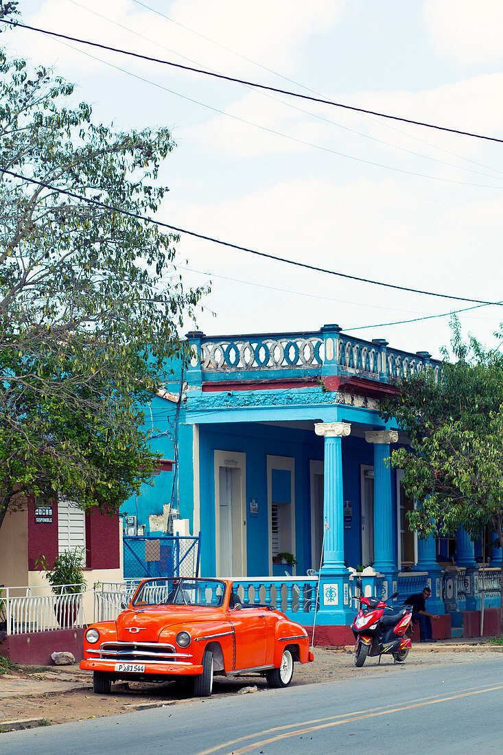 Roter Oldtimer vor einem blauen Gebäude in Vinales, Kuba
