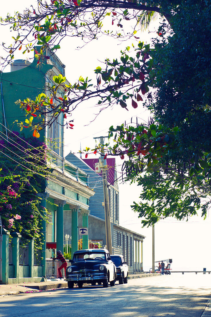 Straßenansicht mit bunten Gebäuden, Blumen und einem Oldtimer in Cienfuegos, Kuba