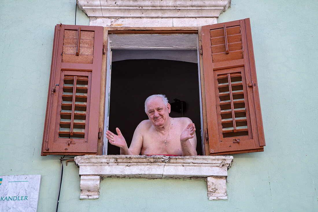 Friendly elderly man with bare chest looking out the window, Pula, Istria, Croatia, Europe