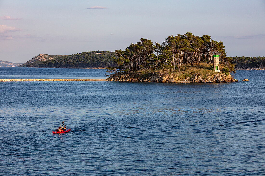 Mann in Seekajak mit Leuchtturm auf Insel in der Ferne, Rab, Primorje-Gorski Kotar, Kroatien, Europa