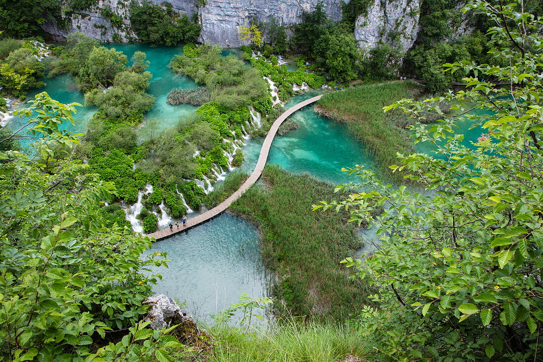 View of people on wooden plank path over pool with waterfalls, Plitvice Lakes National Park, Lika-Senj, Croatia, Europe