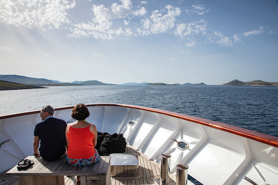 Paar entspannt am Bug von Kreuzfahrtschiff mit Inseln in der Ferne, Kornati Islands National Park, Šibenik-Knin, Kroatien, Europa