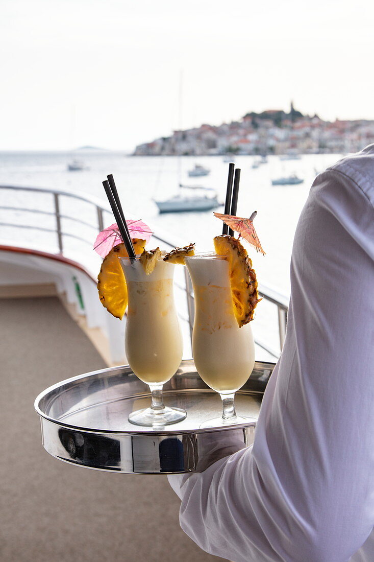 Detail von zwei Cocktails auf Tablett das Kellner an Bord von Kreuzfahrtschiff trägt, Primosten, Šibenik-Knin, Kroatien, Europa