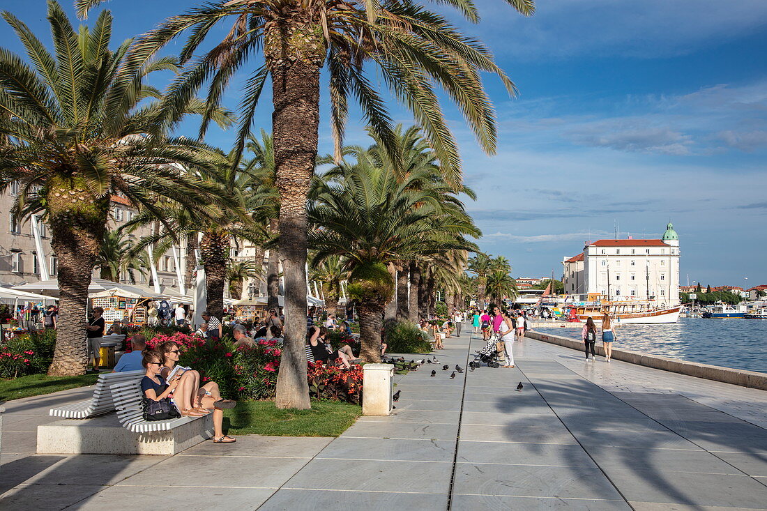 Menschen genießen die Sonne entlang der Strandpromenade mit Palmen, Split, Split-Dalmatien, Kroatien, Europa