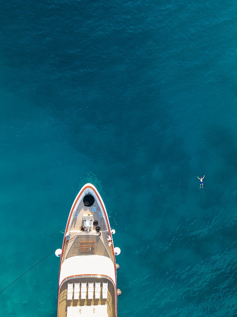 Aerial view of cruise ship with man who swims next to the bow in the water, near Kampor, Primorje-Gorski Kotar, Croatia, Europe