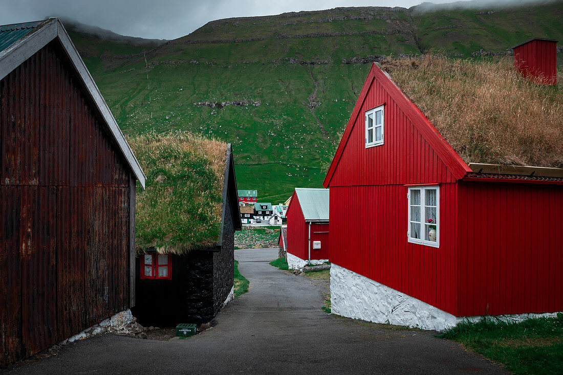 Rote Häuser mit Grasdach im Dorf Elduvík auf Eysturoy, Färöer Inseln\n