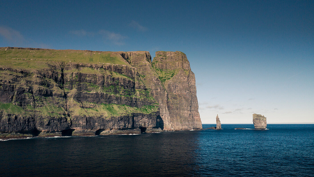 Risin og Kellingin rocks on Faroe Islands during the day with sun and blue sky