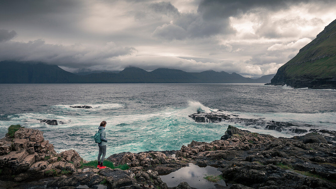 Woman on the coast of Gjogv with waves, Faroe Islands