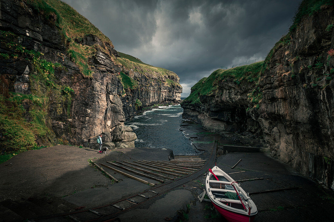Gorge in the village of Gjogv on Eysteroy, with boat and woman, Faroe Islands