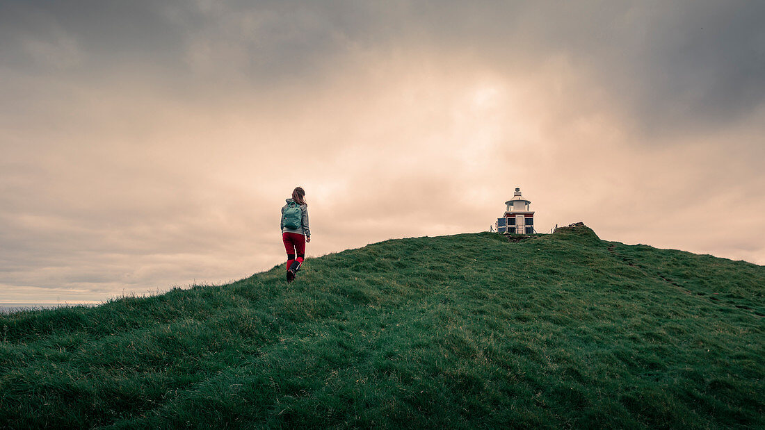 Frau wandert zu Leuchtturm der Insel Kalsoy, Färöer Inseln\n