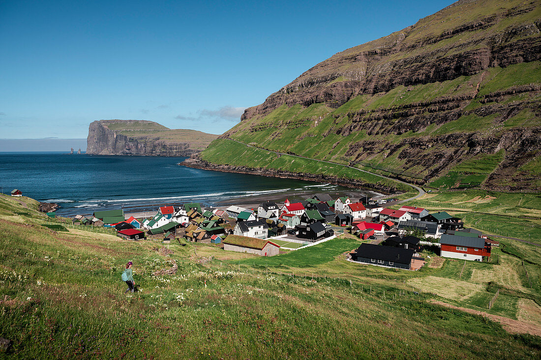 Woman hiking with a view of Tjørnuvík village on Streymoy on Faroe Islands by day