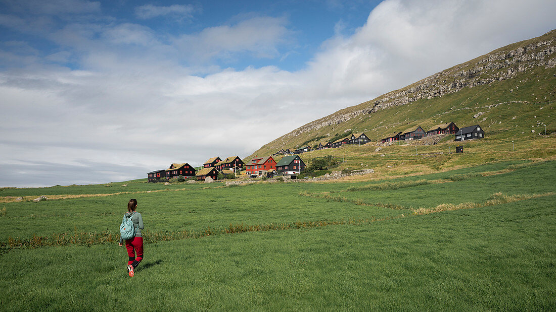Woman hikes to the village of Kirkjubøur on Streymoy, Faroe Islands