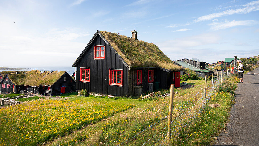 Black houses with red windows and a grass roof in the village of Kirkjubøur on Streymoy in the sun, Faroe Islands