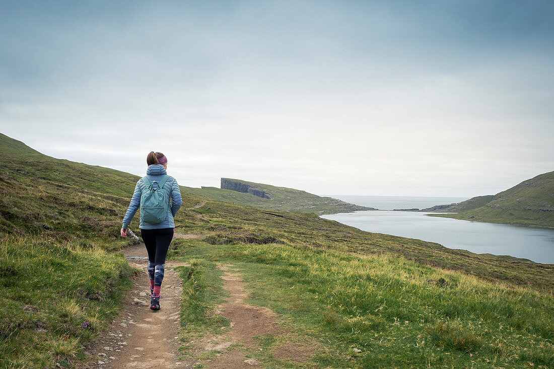 Frau wandert am See Leitisvatn bei Trælanípa auf der Insel Vagar, Färöer Inseln\n