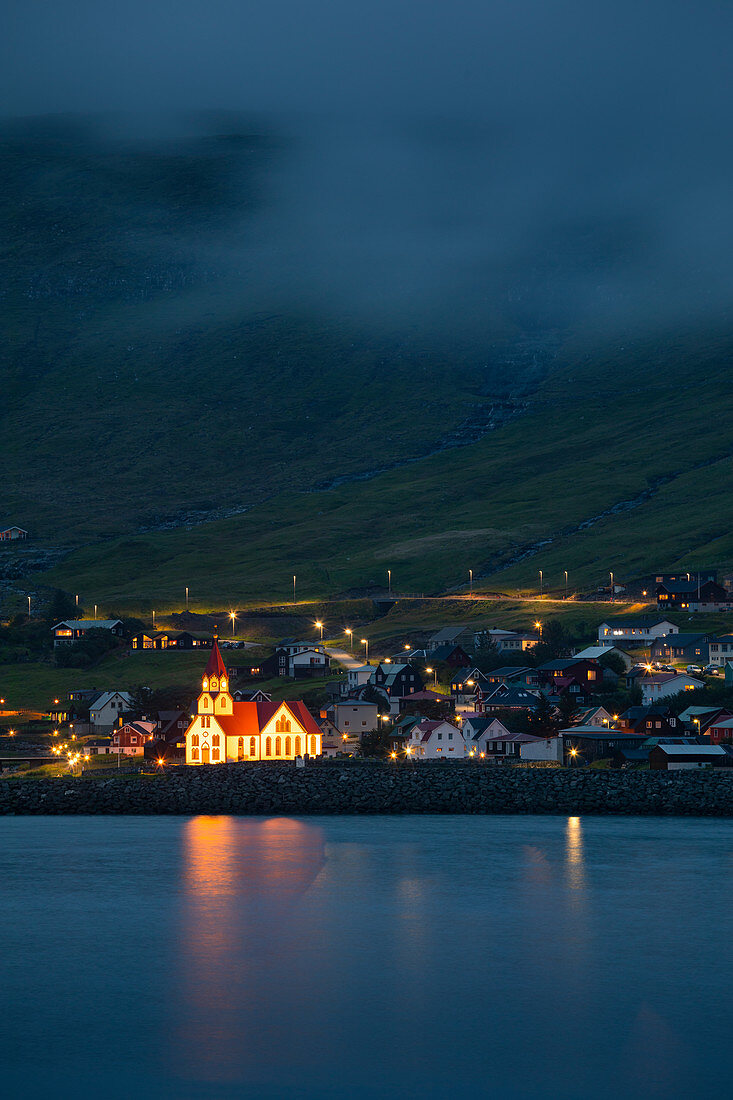 Beleuchtete Kirche bei Nacht im Dorf von Sandavágur auf der Insel Vagar, Färöer Inseln\n