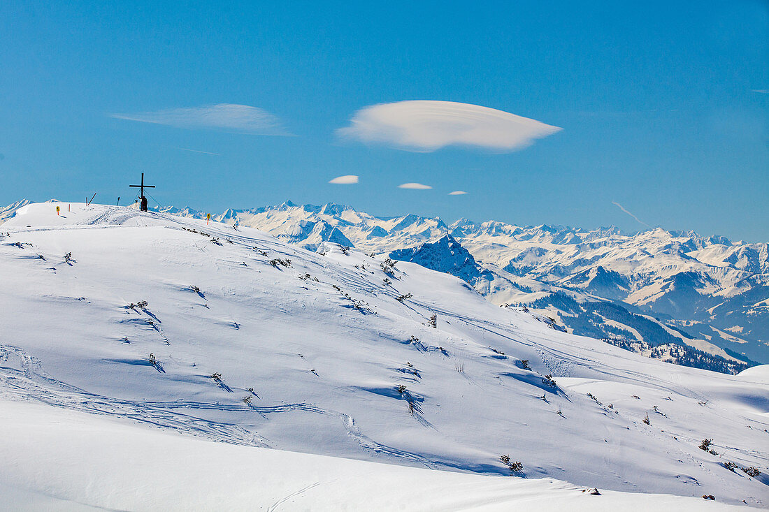 Steinplatte im Winter mit Gipfelkreuz und Tiroler Alpenpanorama, Tirol, Pillerseetal, Österreich