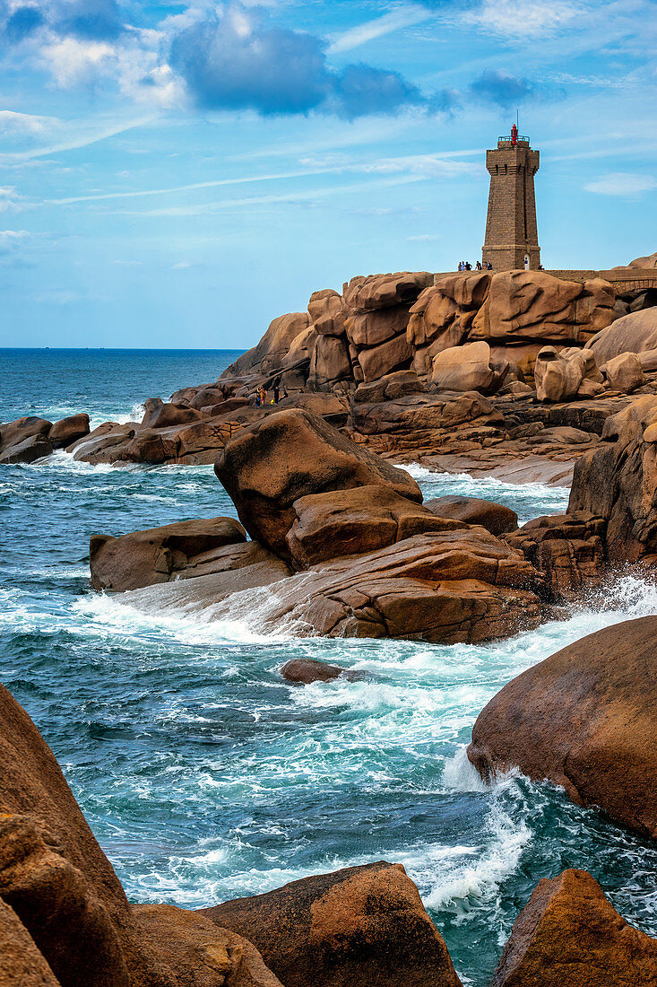 The mean Ruz lighthouse with the red rocks of the Cote de Granit Rose in the foreground, Brittany, France, Europe