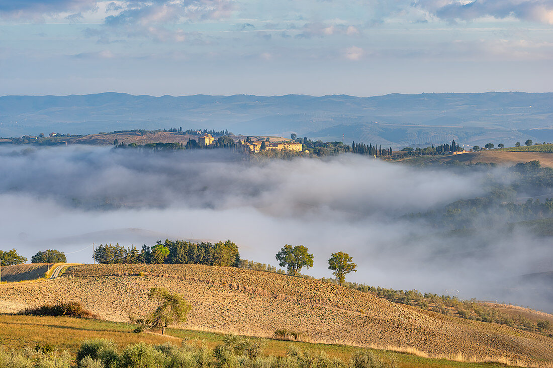 Castello di Porrona near Cinigiano above the Ombrone Valley in the morning mist, Province of Grosseto, Tuscany, Italy