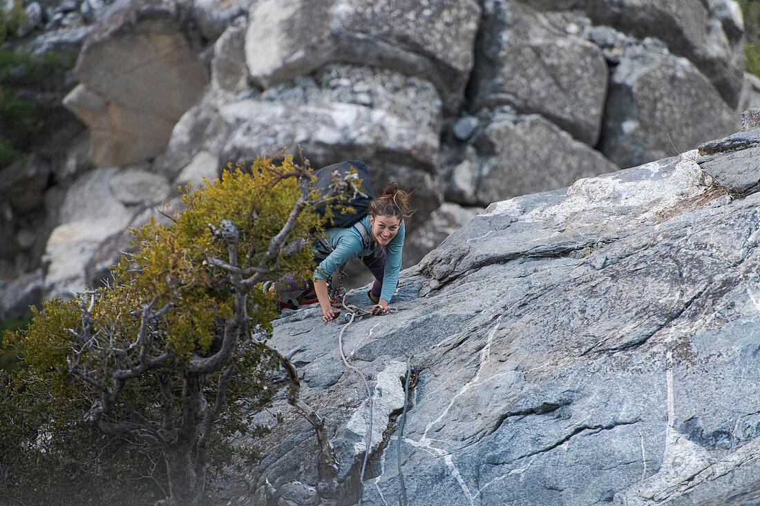 A woman climbing up a rocky slope with ropes.