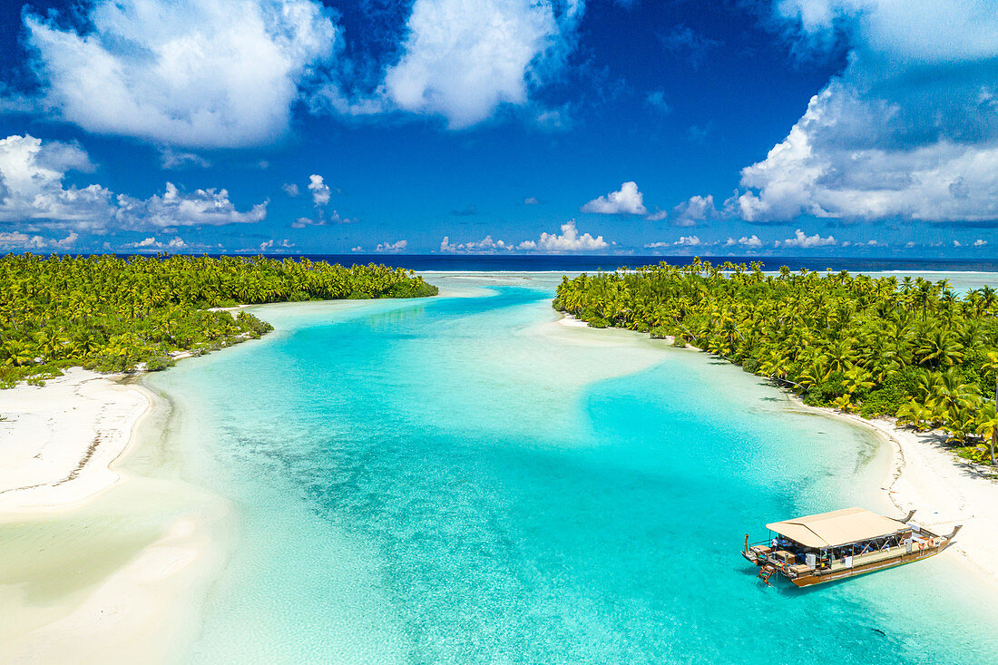 Small boat moored in Aitutaki lagoon, white sand and turquoise shallows.