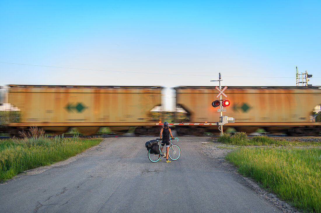 Cyclist waiting for train ahead to pass, Ontario, Canada