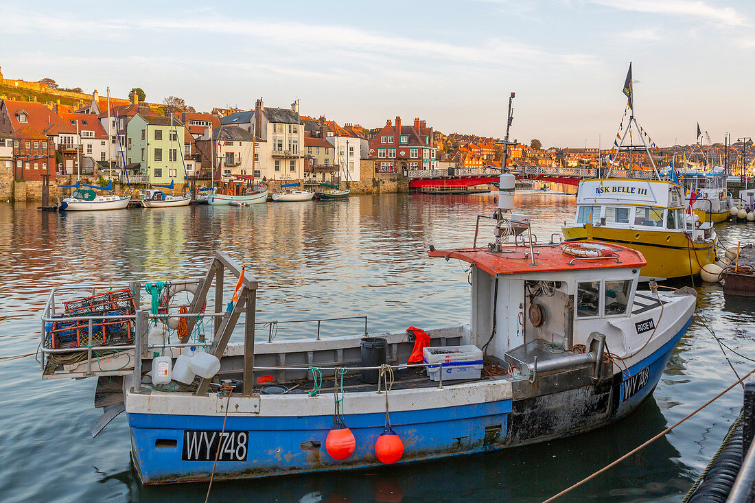 View of riverside houses and fishing boats on River Esk at sunset, Whitby, Yorkshire, England, United Kingdom, Europe