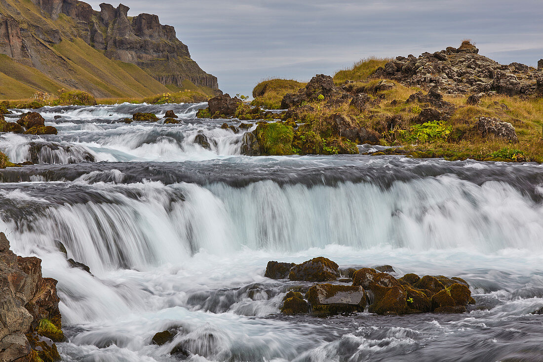 Eine klassische isländische Landschaft, ein Fluss, der am Fuß einer Klippe fließt, The Fossalar River, in der Nähe von Kirkjubaejarklaustur, Island, Polarregionen