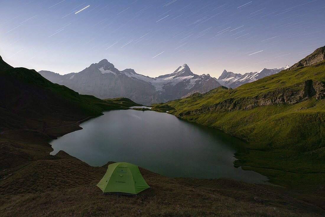 Ein Bergsteiger ruht in einem Zelt während einer klaren Sommernacht am Bachalpsee, Grindelwald, Oberland, Kanton Bern, Schweiz, Europa