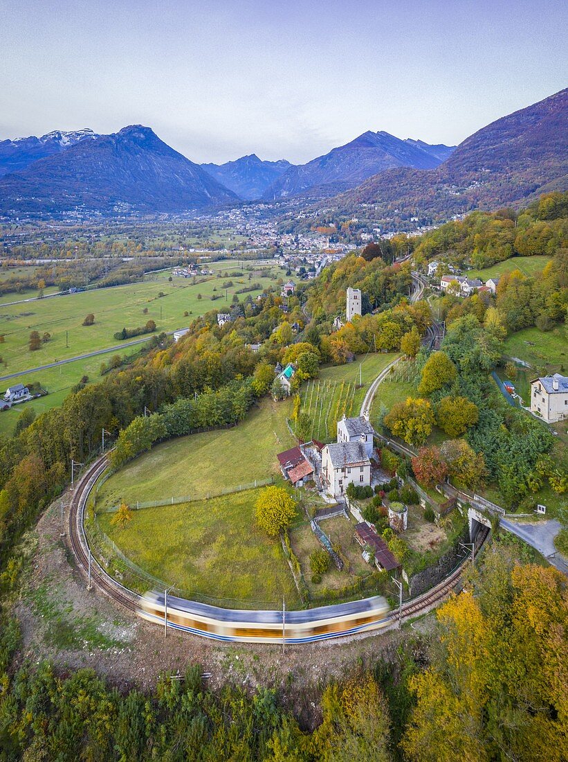 Der Zug Vigezzina-Centovalli fährt in den herbstlichen Laubfarben bei Trontano über eine runde Kurve der Eisenbahn. Valle Vigezzo, Val d'Ossola, Verbano Cusio Ossola, Piemont, Italien.