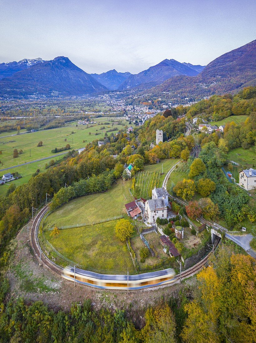 The Vigezzina-Centovalli train passes over a round shape curve of the railway in the autumnal colors of foliage near Trontano. Valle Vigezzo, val d'Ossola, Verbano Cusio Ossola, Piedmont, Italy.