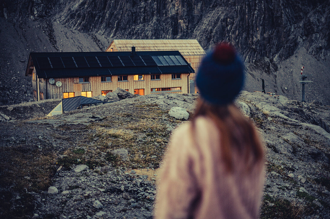 Woman stands during twilight at the Totalphütte in the Rätikon above the Lünersee, Vorarlberg, Austria, Europe