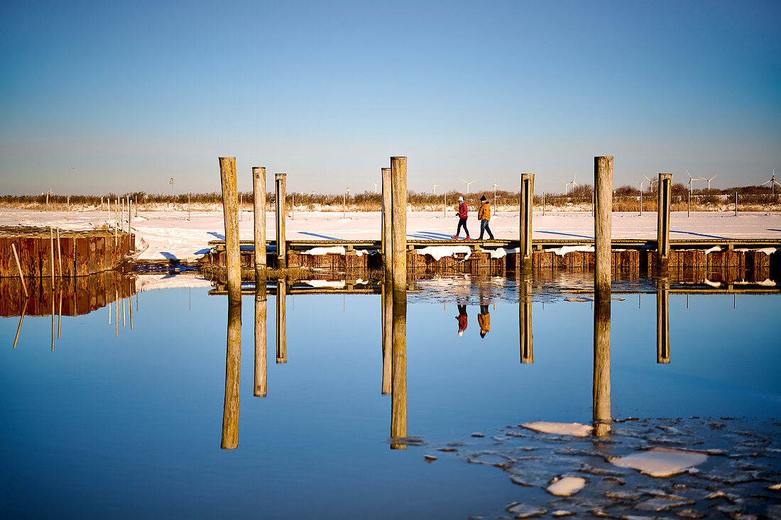 Walkers at the cutter harbor with mirror image, Dorum, Lower Saxony, Germany