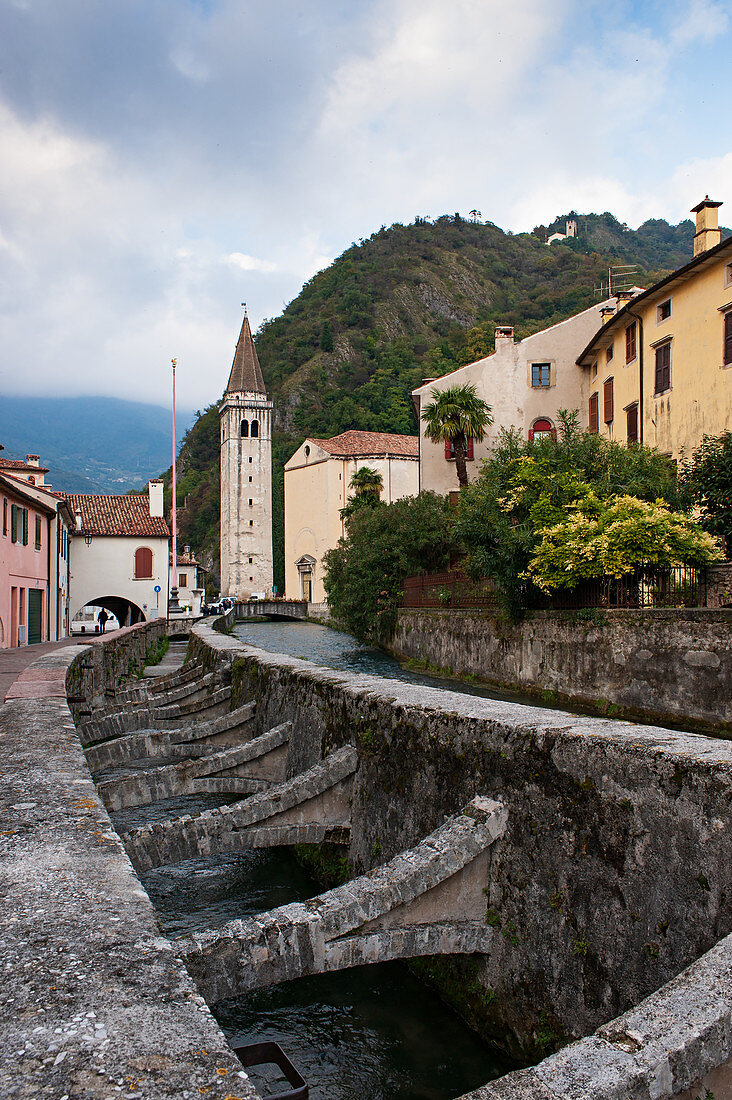 View of the bell tower of the Cathedral of Serravalle district in Vittorio Veneto and the Meschio river. Veneto region. Italy